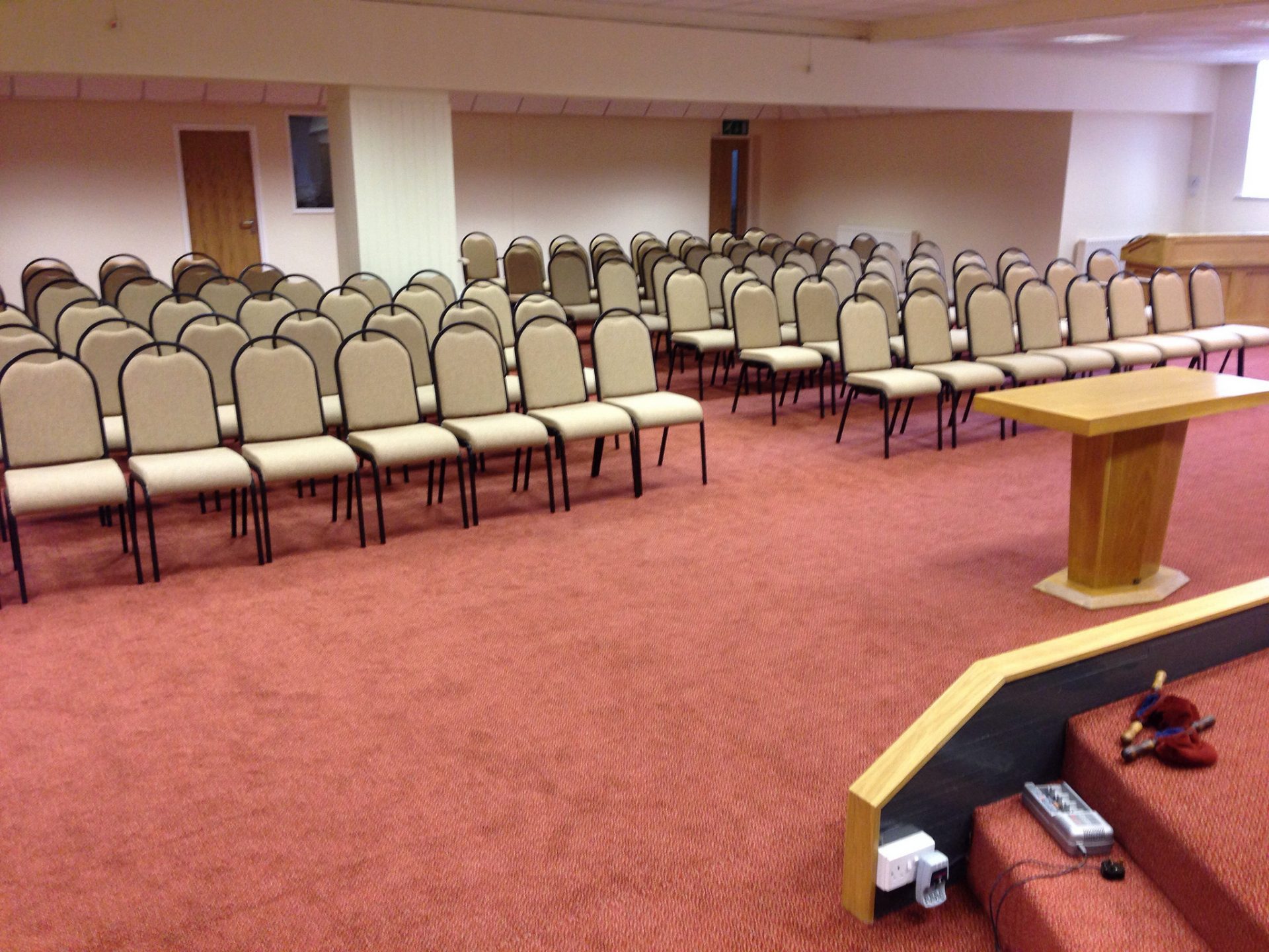 Red commercial carpet fitted through a hall of stacked chairs