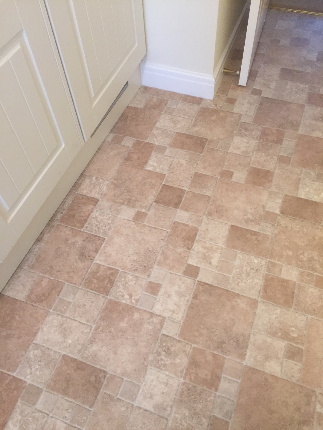 Mixed-size stone-effect tiles fitted against kitchen cabinets