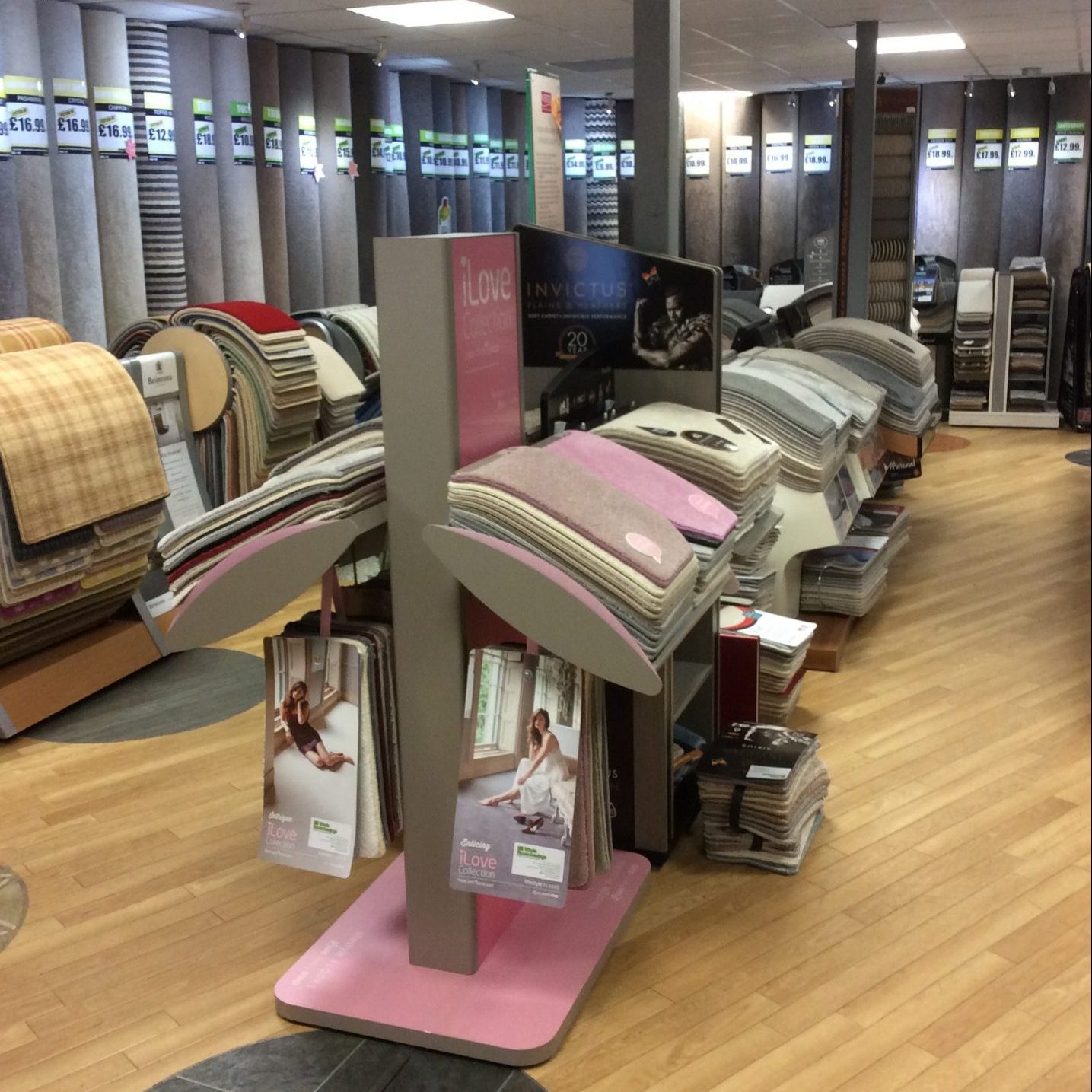 Aisle of carpet rolls and Lifestyle Floors sample stand in the shop